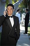 Portrait of boy (13-15) in tuxedo at Quinceanera, using mobile phone