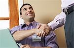 Business man shaking hands with colleague at desk in office