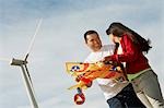 Girl (7-9) holding airplane kite with father at wind farm