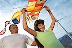 Girl (7-9) holding airplane kite with father at wind farm