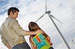 Father embracing daughter (5-6) at wind farm