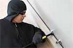 Burglar using crowbar to break into house