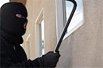 Burglar using crowbar to break into house
