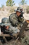 Soldiers aiming machine gun, leaning on log