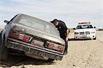 Officier de police à la recherche dans une voiture abandonnée sur le bord de la route