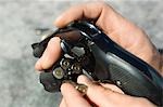 Man loading bullets into gun, close-up of hands