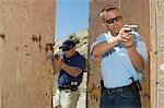 Two men aiming hand guns at firing range