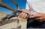 Man loading magazine into gun at firing range, close-up