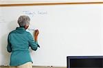 Enseignante d'écriture sur tableau blanc dans la salle de classe
