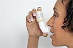 Woman using inhaler, studio shot