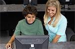 School boy using computer with teacher in classroom