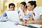 Three business colleagues using laptop in office