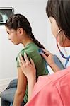 Doctor examining girl using stethoscope in hospital