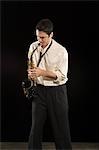 Mid adult man stands in shirt playing the saxophone