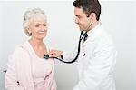 Mid adult doctor checks breathing of senior patient