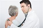 Mid adult doctor checks breathing of senior patient