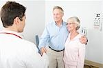 Mid adult doctor shaking hand of senior man in couple