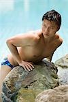 Homme se penchant sur la roche près de piscine