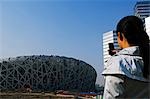 China,Beijing,Olympic Park. A Chinese girl trying to get an early look at the National Stadium for the 2008 Beijing Olympics.