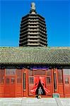 Temple de Chine, Beijing, Tianningsi. Une religieuse de pénétrer dans le bâtiment du temple dominé par une pagode à plusieurs niveaux.