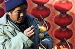 Chine, Beijing. Chinese New année Spring Festival - un homme faire des bonbons de sucre en forme de la souris dans l'année du rat à Longtanhu Fair Park.