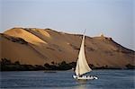 Eine Feluke segelt entlang dem Nil bei Assuan, Ägypten, die Wüste erstreckt sich entfernt, hinter.