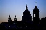 Silhouette of St Pauls Cathedral and one of the towers of Canon Street station against the evening sky.