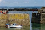 Bateaux de pêche attachés au sein de la sécurité du mur massif port protégeant le port de Mousehole, Cornouailles, Angleterre