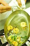 UK,Northern Ireland,Fermanagh,Enniskillen. A chef sprinkles chopped parsley on prawns in the kitchen at Lough Erne Golf Resort.