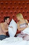 Northern Ireland,Fermanagh,Enniskillen. A couple pillow fighting in bed in the Dovecot Suite at Lough Erne Golf Resort .