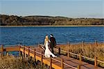 Royaume-Uni, Irlande du Nord, Fermanagh, Enniskillen. Mariée et le marié marchent bras bras le long du ponton au cours de leur mariage à l'hôtel Lough Erne Golf Resort.