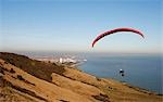 England,East Sussex,Eastbourne. Paragliding is a recreational and competitive flying sport. A paraglider is a free-flying,foot-launched aircraft. The pilot sits in a harness suspended below a fabric wing,whose shape is formed by the pressure of air entering vents in the front of the wing.