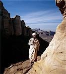 A priest stands outside the rock-hewn church of Abune Yemata in the Gheralta Mountains near Guh.Carved into a cliff face with a sheer drop of 800 to 1,000 feet,the church is reached only by a hazardous ascent with tiny footholds and irregular hand grips. It is renowned for its truly remarkable murals.