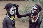 A young Karo girl decorates her friends face. A small Omotic tribe related to the Hamar,who live along the banks of the Omo River in southwestern Ethiopia,the Karo are renowned for their elaborate body painting using white chalk,crushed rock and other natural pigments.