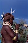 A Hamar woman blows a tin horn at the bull -jumping ceremony of a man in her family,a rite of passage to manhood. She wears a leather belt decorated with cowrie shells around her neck. As is normal for her tribe she wears her hair braided and thick with ochre and animal fat.