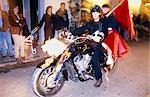 Couple sitting on motorbike dressed for Carnival in Ibiza