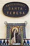 A painted ceramic mural depicting Santa Teresa praying before a cross,on a wall in Seville,Spain