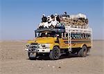 A heavily-laden bus travels across the Nubian Desert east of the River Nile in Northern Sudan.