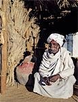 Un homme nubien s'accroupit à côté d'un vieux réservoir d'eau dans une oasis dans le désert de Nubie au nord de Old Dongola.