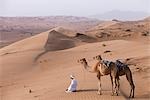 Ein Bedu kniet in der Wüste beten halten seine Kamele durch ihre Halfter, damit sie nicht unter die DunesOman OM3 John Warburton-Lee aus Wandern