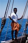 One of the crew members of S/Y Sanjeeda standing on the rail of the boat. Sanjeeda is a traditional kotiya dhow of the type that traded throughout the Indian Ocean