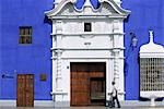 A man passes the intricate ironwork and pastel shades of a colonial mansion on the Plaza de Armas in Trujillo,Peru