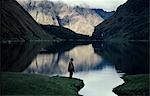 A high lake in the Vilcabamba range; at the waters edge a mule wrangler checks his fishing line at dawn.