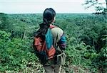 A local ecotourism guide surveys the lowland forest from a ridge. In her daypack she carries binoculars,bird book and first aid. Bird watching is popular here where the world record for species diversity is held.