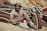 Potato harvesting in fields in the highlands. An old man leans against the raw llama wool sacks. Each stripe the colour of the animal it came from. There are over 200 species of potato and nearly 3,000 varieties in this country that was there origin. The domestication of the potato,maize,llama and guinea pig were the foundation upon which the early andean civilisations were built.