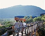 Laundry Ladies carry the laundry in baskets balanced on their heads as they cross the wooden bridge to the guests' chalets at Kwandwe Lodge.