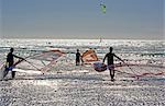 South Africa,Western Cape,Cape Town. Windsurfers leave a blustery Table Bay on the beach at Melkbosstrand.