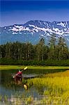 Homme en kayak pagaie dans un petit lac dans la vallée de Portage, centre-sud de l'Alaska, l'été