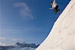 Hikers leaping from snowy ridge while exploring the Juneau Ice Field, Tongass National Forest, Alaska/n