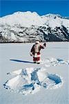 Santa ondulation après avoir fait un ange de neige dans la neige fraîche